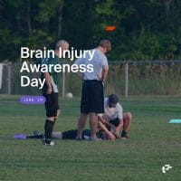 Three youth soccer players stand over a fourth soccer player who is laying down on their back on the soccer field. Text reads: "Brain Injury Awareness Day. June 29."